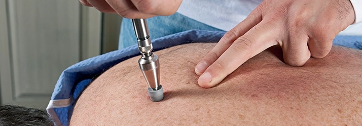 Chiropractic Kalamazoo MI Activator Method Instrument The Activator Method on patients back.