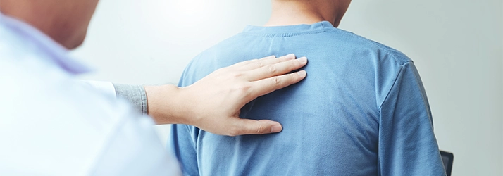 Chiropractor with his hand on a patients back.