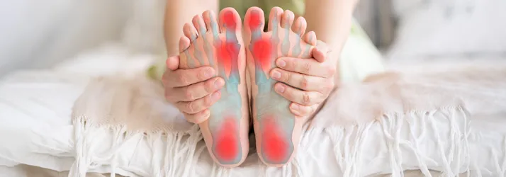 Chiropractic Kalamazoo MI Foot Pain Person sitting on a bed holding their feet.
