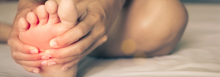 Person holding their foot in pain.